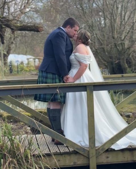 Newlyweds sharing a romantic moment in the Scottish Highlands during their wedding day.